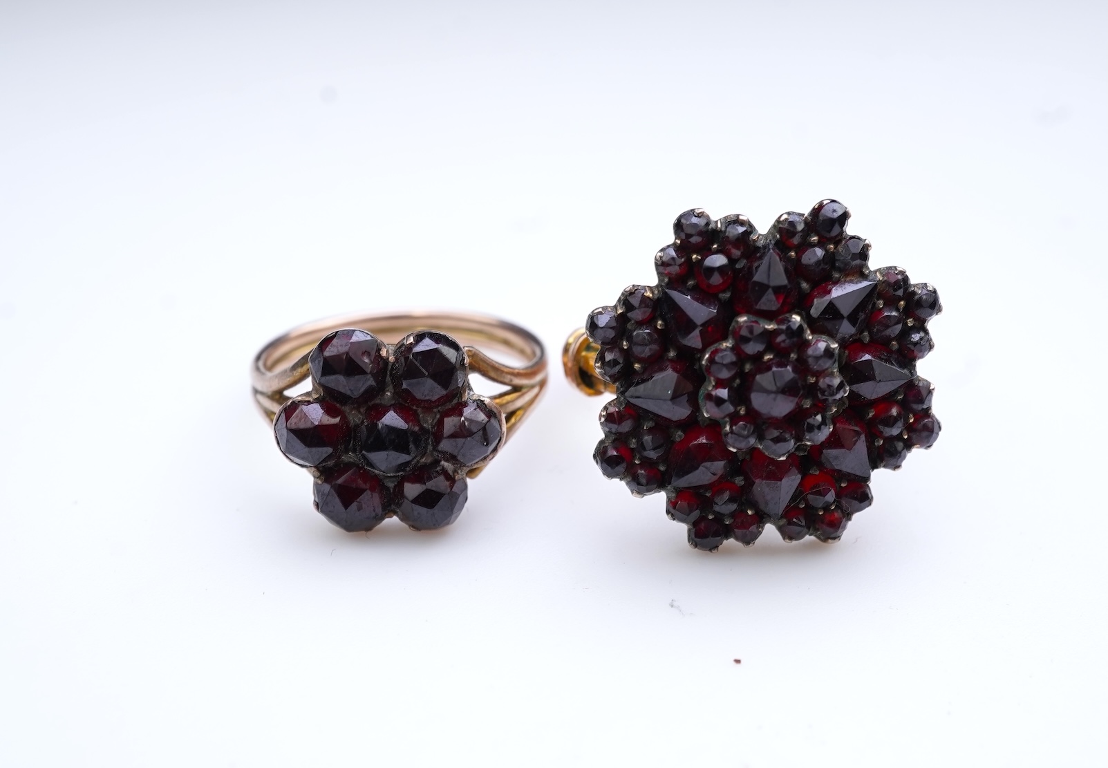 A suite of garnet and paste jewellery, comprising: a brooch, 5cm diameter; a bangle, inner circumference 16cm; two rings, sizes I and M; a pair of earrings, and a single earring, each set with rose-cut garnets; and a pai